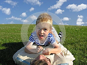 Son lie on father on green grass