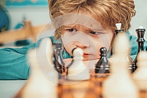 Son are playing chess and smiling at home. Kids chess school. Little clever boy thinking about chess.