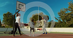 Son playing passing basketball with father and mother.