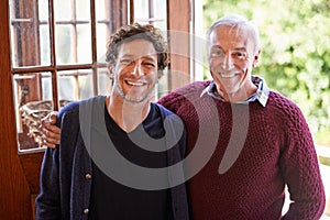 Son, senior dad and portrait in home by front door with hug, smile and bonding with connection. Men, elderly father and