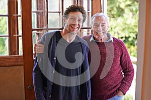 Son, senior father and portrait in home by front door with hug, smile and bonding with connection. Men, elderly dad and