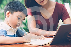 Son using digital tablet computer for study and learn to internet online with mother together.