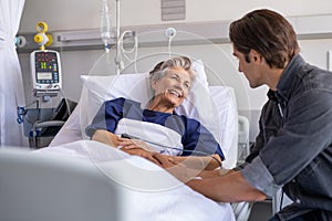 Son visiting his smiling mother at hospital