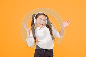 The song clicks with her mood. Adorable little girl singing a song on yellow background. Cute small child listening to