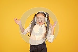 The song clicks with her mood. Adorable little girl singing a song on yellow background. Cute small child listening to