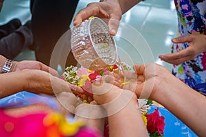 Songkran festival sign of Thailand : Hand of young people pour water, flowers on older. Thais celebrate Songkran in new year water