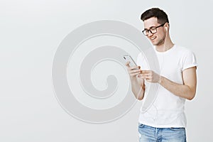 With songs through life. Portrait of happy and satisfied handsome european man installing cool music app on smartphone