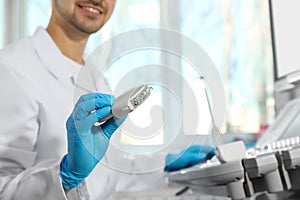 Sonographer holding ultrasound machine probe with gel in clinic, closeup