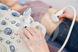 Sonographer pressing ultrasonic transducer against woman stomach area