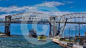 Soo locks tour boat passes under the international Bridge into Canada with a freighter in saulte Ste Marie Michigan