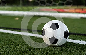 A soocer or football on a field of green with goal in background