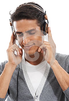 Soothing tunes...A handsome young man enjoying music through his headphones with his eyes closed.