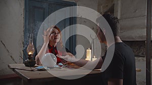 Soothsayer palm reading to man in rustic house