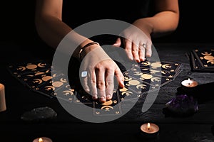 Soothsayer predicting future with tarot cards at table in darkness, closeup