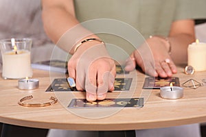 Soothsayer predicting future with tarot cards at table indoors, closeup