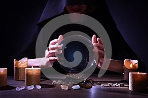 Soothsayer using crystal ball to predict future at table in darkness, closeup. Fortune telling