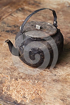 Sooty old teapot on old table in open kitchen