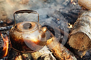 Sooty teapot on camping bonfire