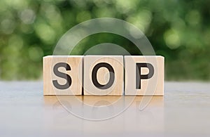 SOP - acronym from wooden blocks with letters, abbreviation SOP standard operating procedure concept, blur background