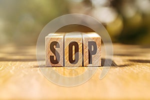 SOP - acronym from wooden blocks with letters, abbreviation SOP standard operating procedure concept, blur background