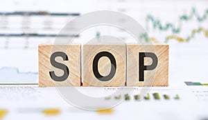 SOP or Standard Operating Procedure - acronym on wooden cubes on a financil background. Business concept