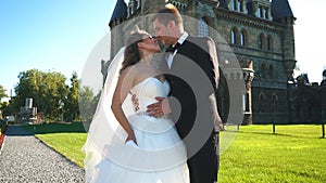 Sophisticated bride and groom kissing near castle. Wedding couple walking in oldest castle