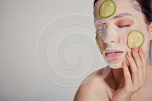 Sophisticated girl in a moisturizing mask with a fresh cucumber on the face