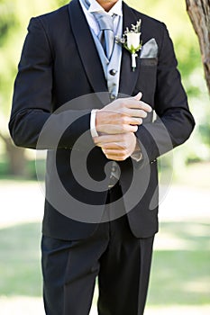 Sophisticated groom adjusting sleeve in garden