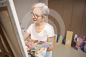 Sophisticated lady is painting a picture in a bright room