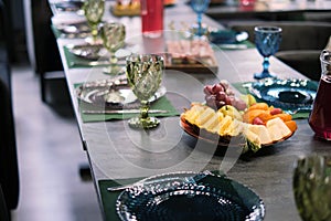 Sophisticated table arrangement, green glassware in focus, with a spread of tropical fruits. Highlights the fusion of