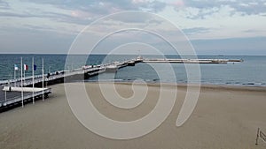 Sopot resort in Poland. Wooden pier (molo) with promenade, marina, yachts, pirate tourist ship, beach, old lighthouse.