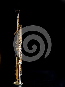 Soprano Sax, wind instrument saxophone staying on a black background, vertical, copy space
