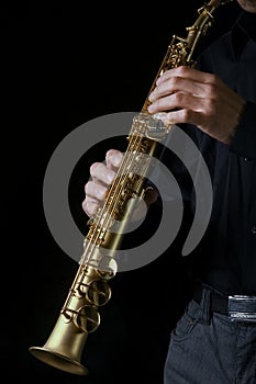 soprano saxophone in hands on a black background photo