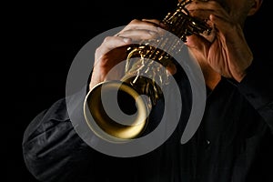 Soprano saxophone in hands on a black background photo
