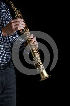 soprano saxophone in hands on a black background photo