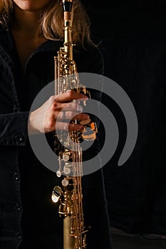 soprano saxophone in the hands of a girl on a black background photo