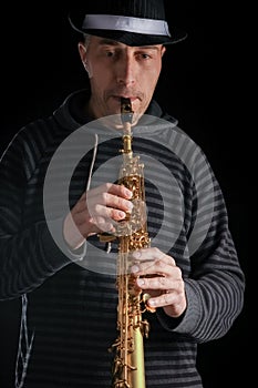 soprano saxophone in the hands of a guy on a black background photo