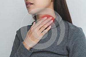 Sore throat in flu season. Young woman touching her neck and feeling pain in throat in the bedroom at home photo