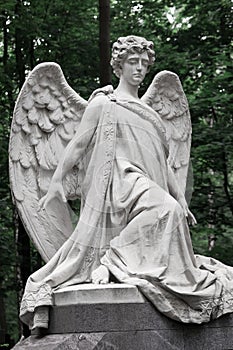 The Sorrowful Angel. Marble mourning angel on a background of g