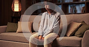 Sorrowful Caucasian Woman on the Sofa in the Living Room in the Evening