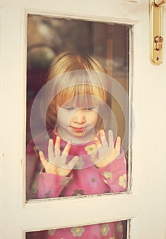 Sorrowful child stand at door window