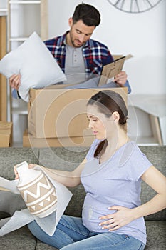 sorrowful pregnant woman looking at boxes with things photo