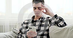 Sorrowful Young Man on Sofa with Phone