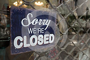 ` Sorry we are closed ` retro wooden sign in front of closed shop.