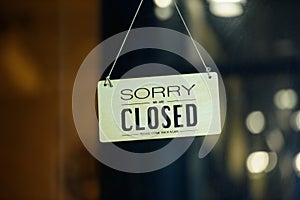 Sorry we are closed sign hanging outside a restaurant, store, office or other. Closed sign in a shop showroom with reflections bok