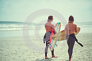 Sorry we couldnt make it, we had a boarding meeting. a young couple walking on the beach with their surfboards.