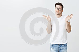 Sorry, my bad. Portrait of silly handsome young male model shrugging with raised palms near shoulders and light smirk