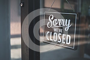 Sorry we\'re closed sign. grunge image hanging on cafe glass door.