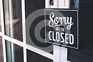 Sorry we're closed sign. grunge image hanging on cafe glass door