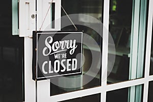 Sorry we're closed sign. grunge image hanging on cafe glass door